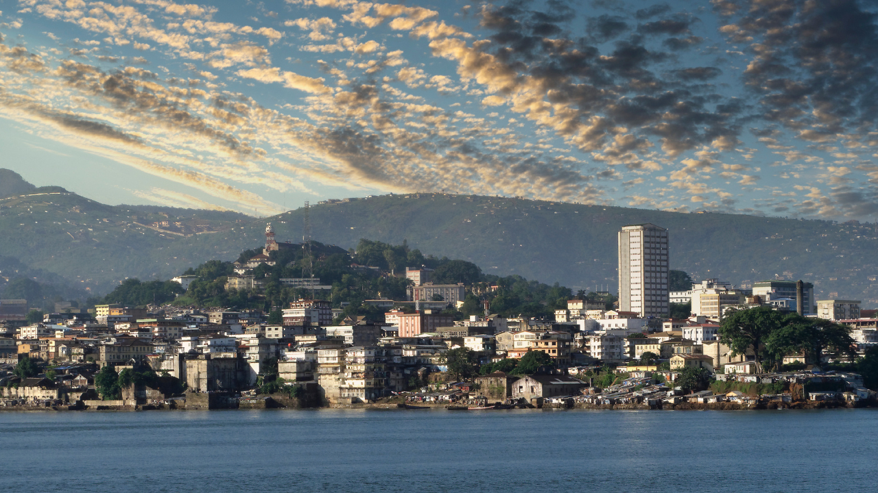 Panoramic view of the Freetown, Sierra Leone, skyline and harbor at sunset, showing coastal development and opportunities for business expansion.