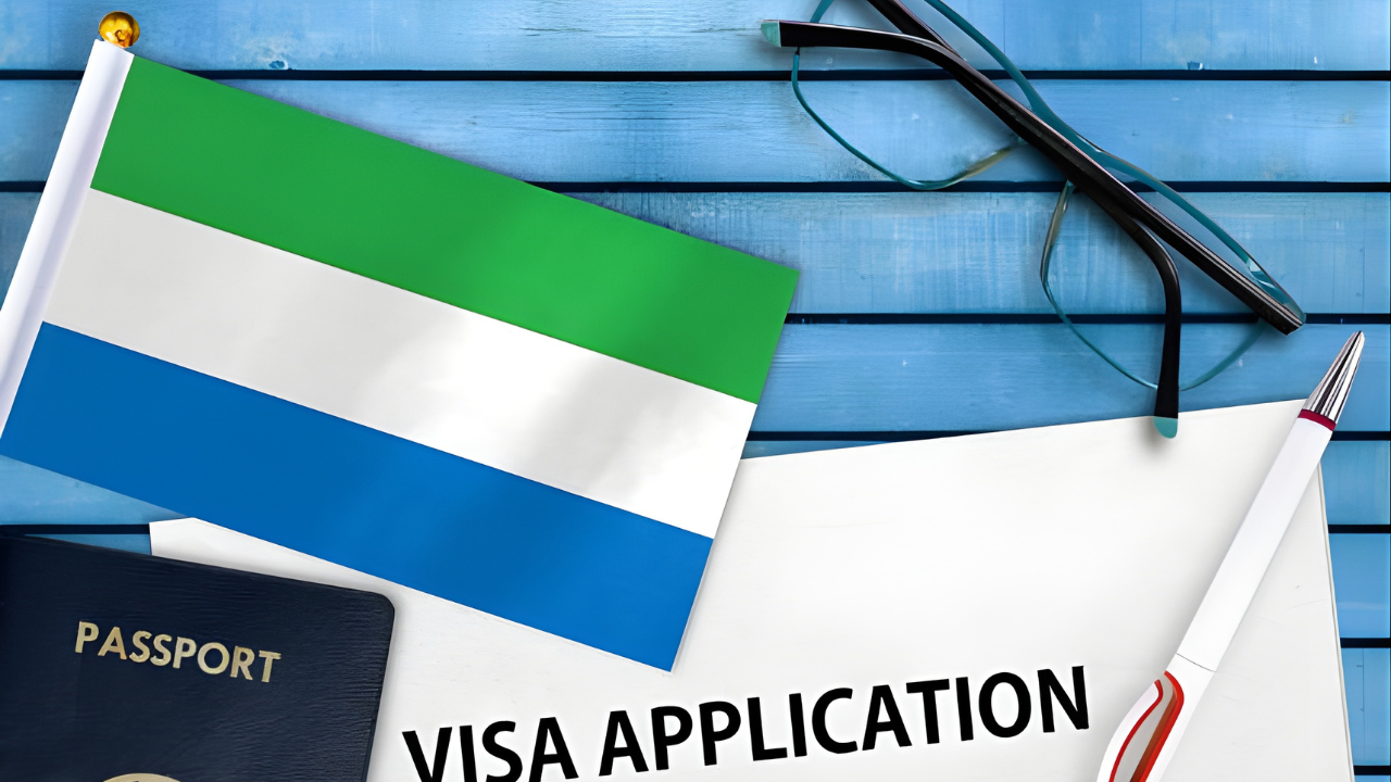 Sierra Leone flag, passport, and a 'VISA APPLICATION' document on a desk, representing the process for obtaining a Sierra Leone Work Permit.